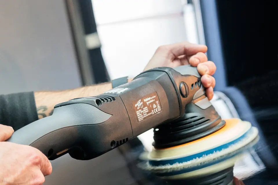 Machine polisher working on a dark car panel