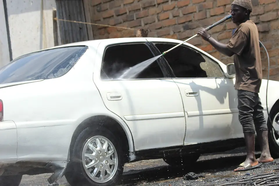 Rinsing a white sedan with a pressure washer